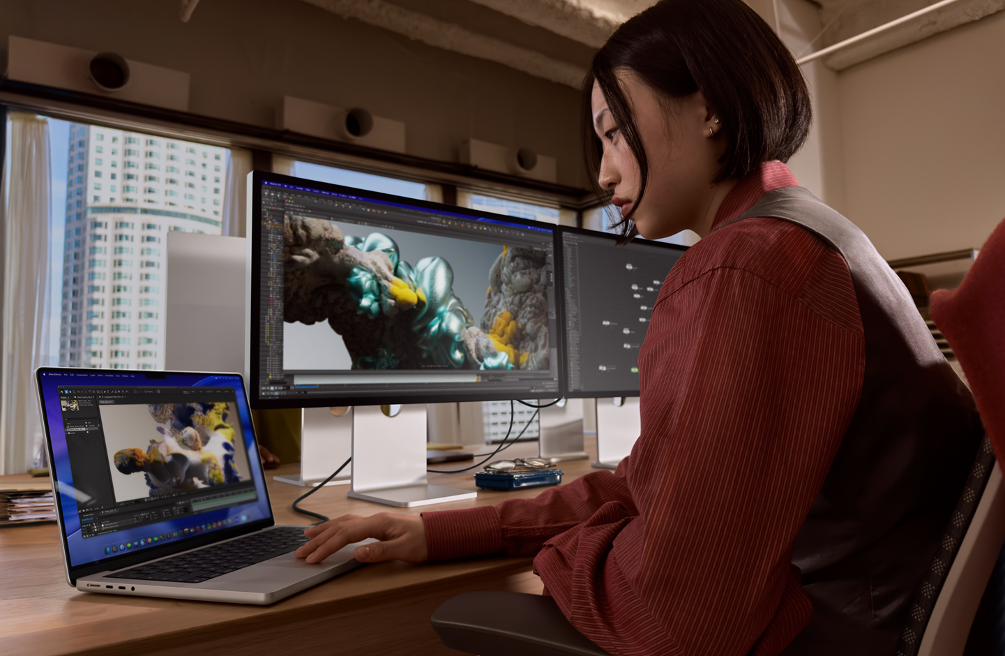 Човек в офис работи с MacBook лаптоп, който е свързан със Studio Display XDR чрез Thunderbolt 5 порт