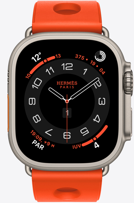 Apple Watch Hermès Ultra 3, cadran analogique Circulaire (aiguilles pour les heures, les minutes et les secondes, complications : météo, anneaux d’activité, heure de Paris, indice UV); boîtier en titane, naturel, côté droit extérieur : couronne Digital Crown, bouton latéral surélevé; jumelé au bracelet Scub’H Diving, orange néon (orange vif), en caoutchouc moulé, découpes circulaires centrées