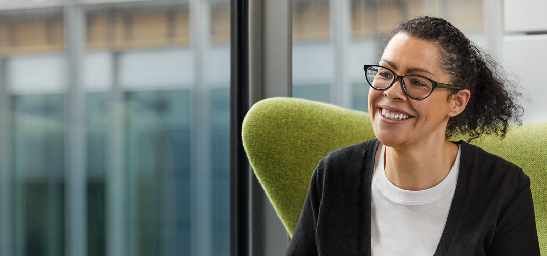 Karen 微笑坐在一張綠色椅子上。