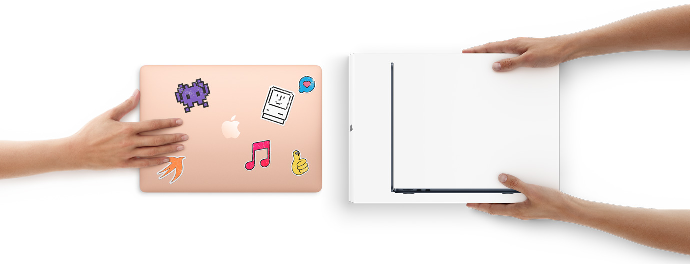 A hand slides a MacBook with stickers on the cover toward two hands holding a new MacBook in the box
