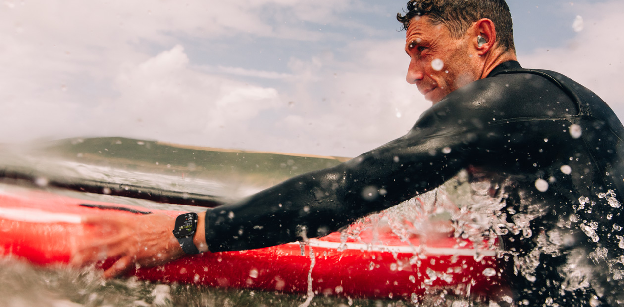 Een man surft en draagt een Apple Watch.