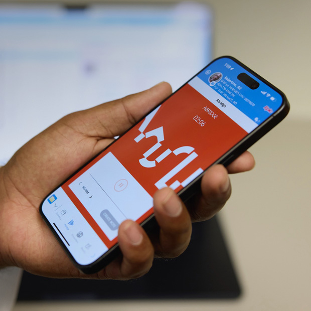 En hånd som holder en iPhone med Abridge-appen, som oversetter samtaler til notater.