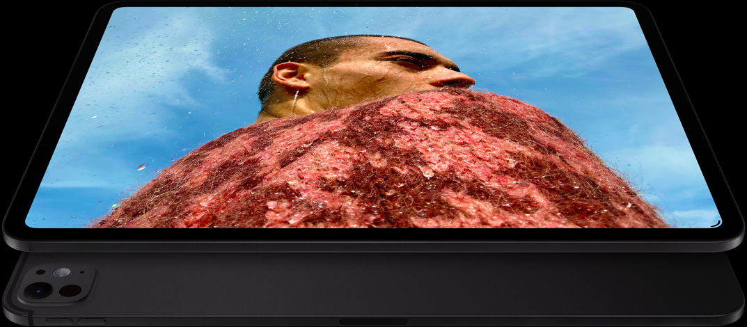 „iPad Pro“, priekinė pusė, horizontalioje padėtyje, kosminės juodos spalvos, užapvalinti kampai, juodas ekrano rėmelis, ekrane rodomas vyras su raudonu megztiniu po mėlynu dangumi, apačioje – kitas „iPad Pro“, galinė pusė, horizontalioje padėtyje, kosminės juodos spalvos, profesionali kamerų sistema, garsumo didinimo ir mažinimo mygtukai