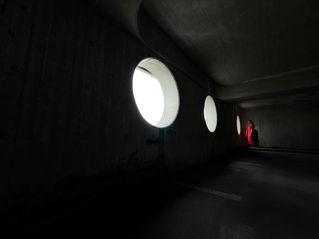 Pitkään, punaiseen leninkiin pukeutunut nainen seisoo tyhjässä huoneessa valokuvattavana. Ammattitason kamerajärjestelmän ominaisuuksia esitellään Kuvat-apissa polttovälejä vaihtamalla, esittelyssä 13 mm