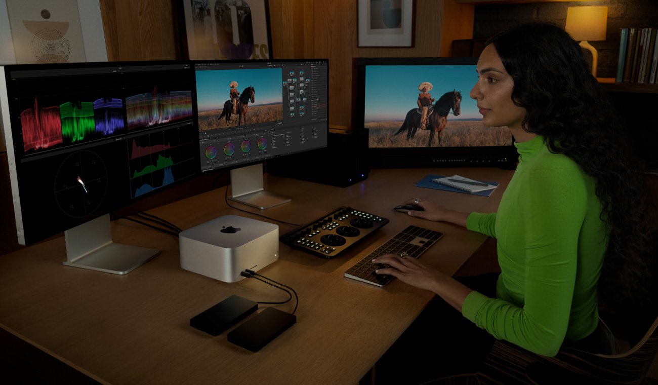 En profesjonell bruker redigerer filer på en Mac Studio med tre skjermer