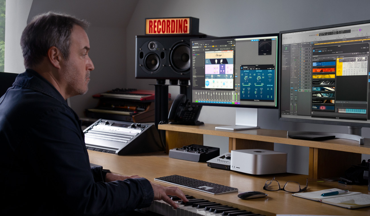 En musiker bruker et piano til å lage lydmikser med Mac Studio og Studio Display