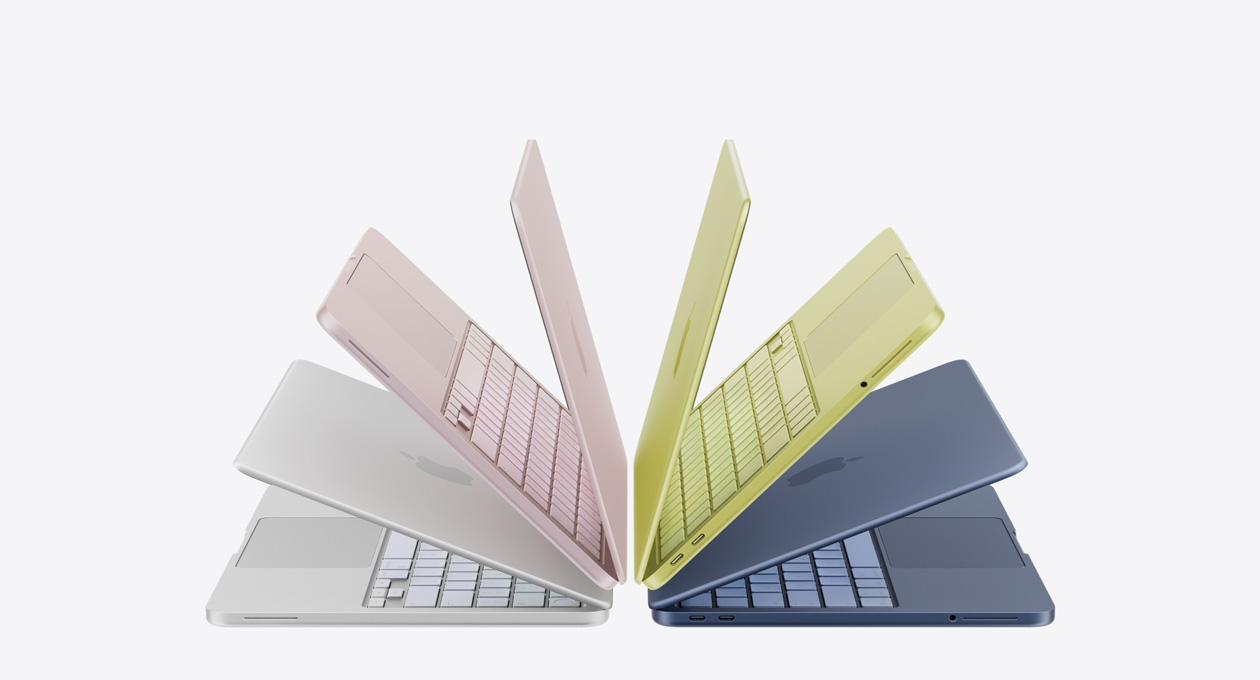 MacBook Neo laptops in silver, blush, citrus, and indigo colors, slightly open and arranged in an arch formation