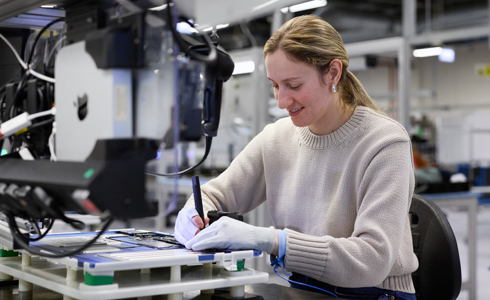 An employee sits at a work station focusing on the tools and product pieces they are holding
